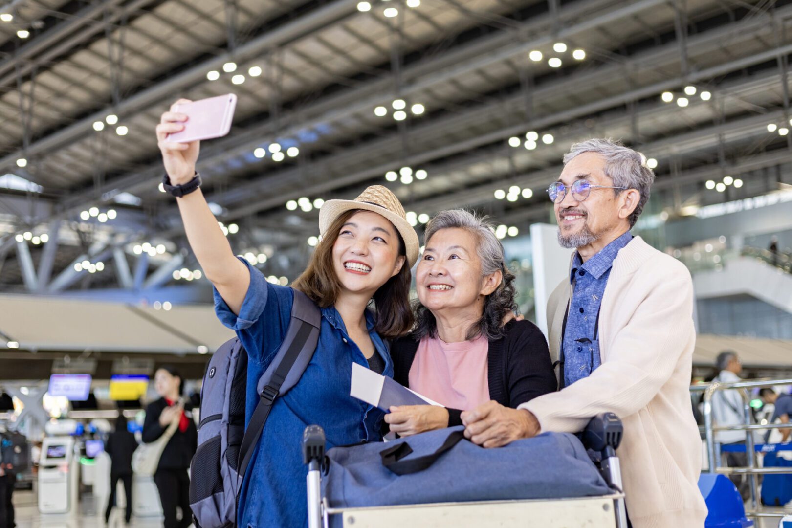 Group of Asian family tourist passengers with senior is using mobile phone to take selfie photo at airport terminal during vacation travel and long weekend holiday Group of Asian family tourist passengers with senior is using mobile phone to take selfie photo at airport terminal during vacation travel and long weekend holiday concept