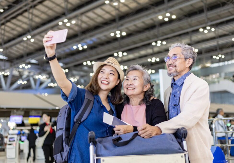 Group of Asian family tourist passengers with senior is using mobile phone to take selfie photo at airport terminal during vacation travel and long weekend holiday Group of Asian family tourist passengers with senior is using mobile phone to take selfie photo at airport terminal during vacation travel and long weekend holiday concept